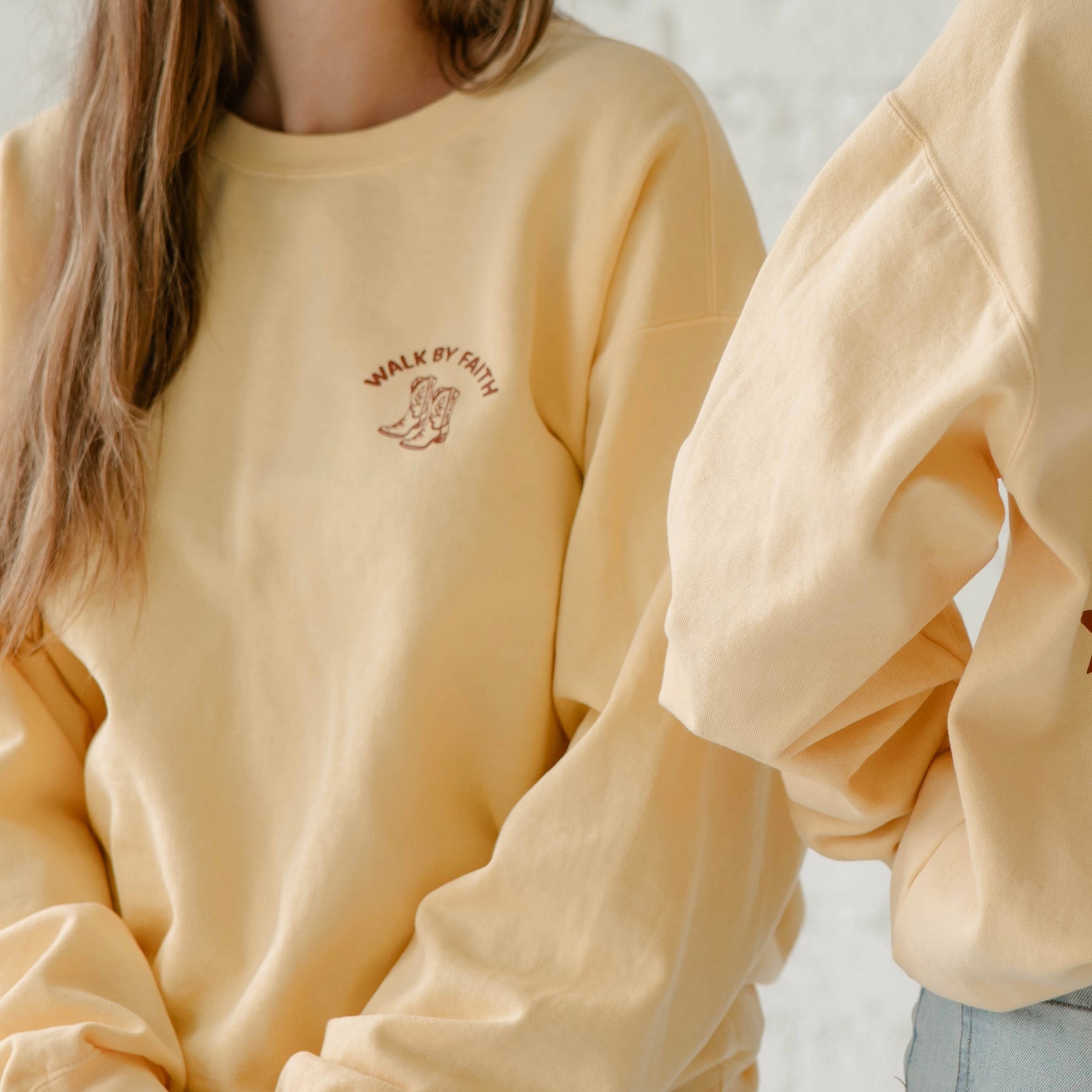 Yellow sweatshirt with text and graphics worn by a person, on a neutral background