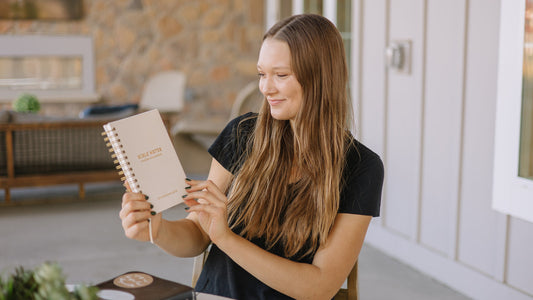 Woman holding the Steadfast and Sustained Bible Notes journal for Scripture study
