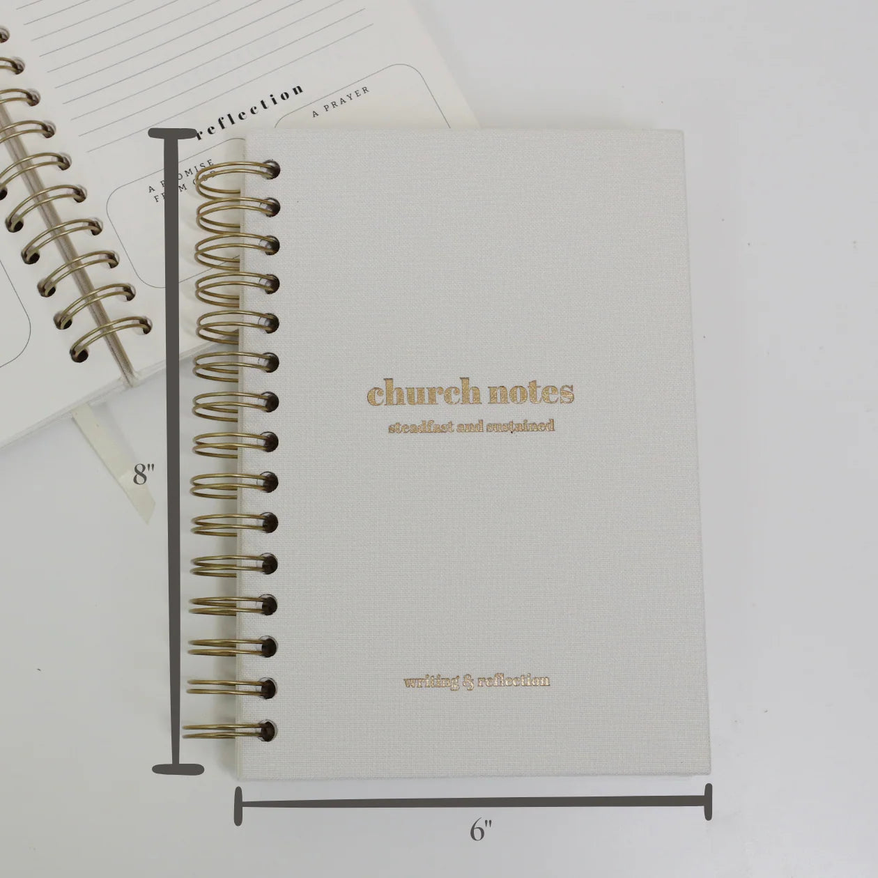 White linen spiral church notes journal with gold spiral binding, showing cover and size dimensions with interior page visible