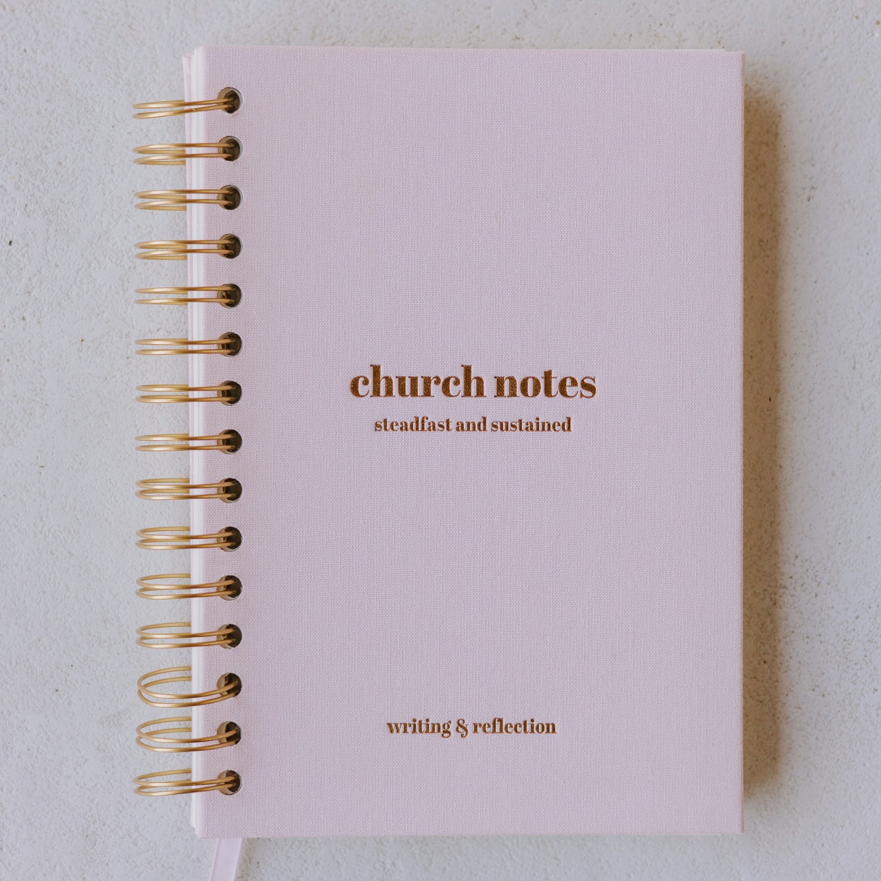 Pink notebook with gold text on a light gray background