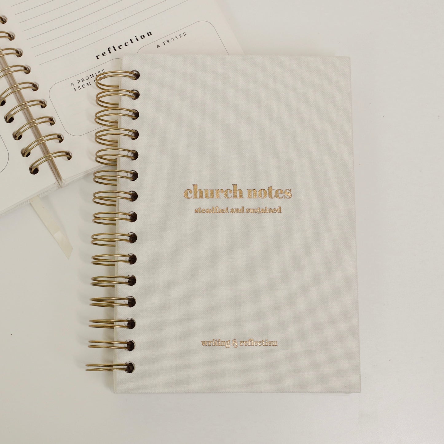 A white spiral-bound journal with linen hardcover and gold text detailing. The journal is titled 'church notes' and has 'writing & reflecting' printed on the cover.